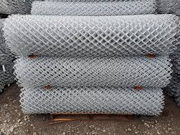 9GA chain link fence mesh rolls stacked for sale, strong and durable outdoor fencing solution.